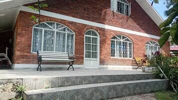 A brick building with large arched windows and a bench outside.
