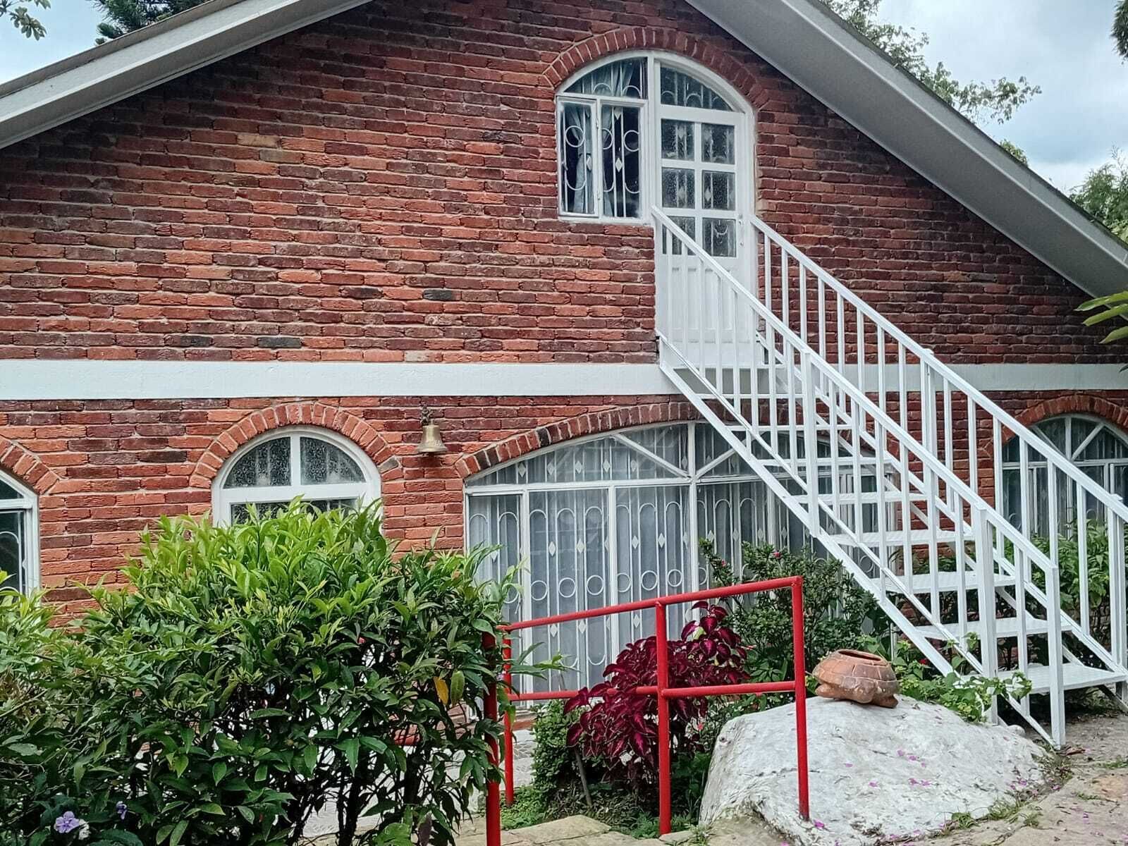 Un edificio de ladrillo rojo con una escalera blanca que lleva a una puerta con un ventanal.