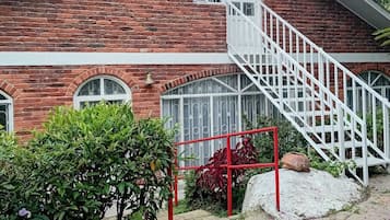 Un bâtiment en briques rouges avec un escalier blanc menant à une porte dotée d’une fenêtre.