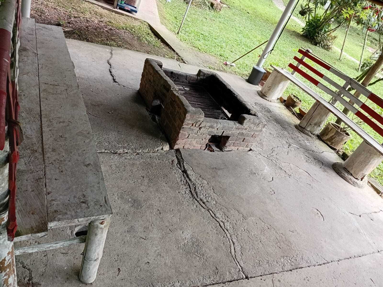 Un espace extérieur en béton, agrémenté d’une structure en briques, qui pourrait servir de barbecue ou de grill, et délimité par une clôture en métal.