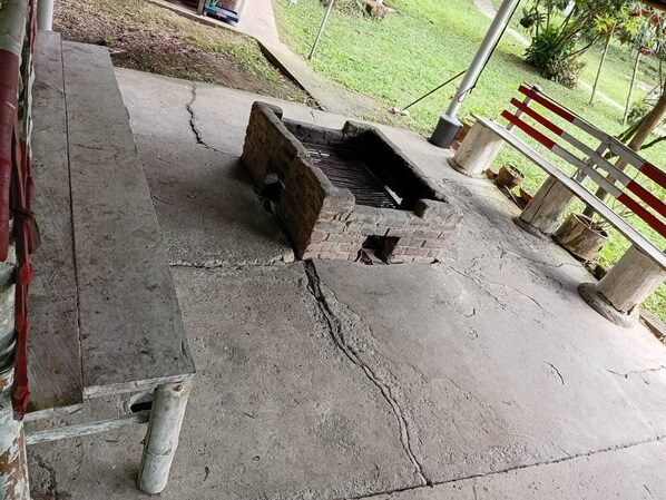 A concrete outdoor area with a brick structure, possibly a barbecue or grill, and a metal fence.