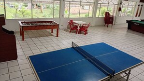 A room with a foosball table, a ping pong table, and a pool table.