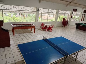 A room with a foosball table, a ping pong table, and a pool table.
