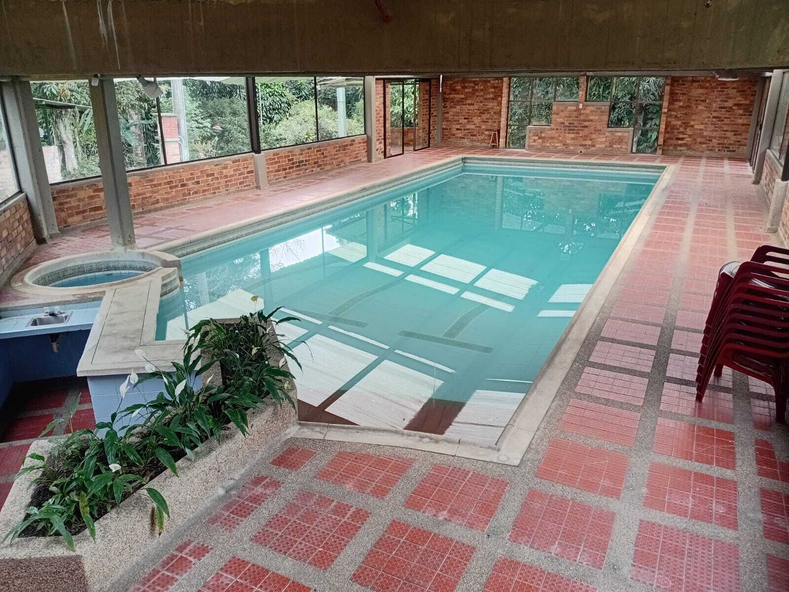 Une piscine intérieure avec un jacuzzi, entourée de murs en briques et dotée de grandes fenêtres.