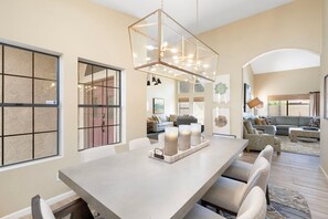 A spacious living area with a long dining table, multiple seating options, and a modern chandelier. - Desert Retreat with Pool Near Golf & Hiking (Scottsdale)