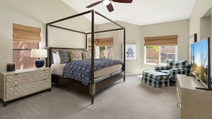 Une chambre à coucher avec un lit à baldaquin, une table de chevet, une commode, un ventilateur de plafond et un téléviseur.