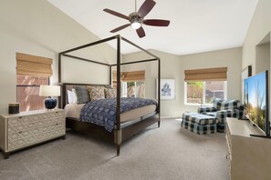 Ein Schlafzimmer mit Himmelbett, Nachttisch, Kommode, Deckenventilator und Fernseher.