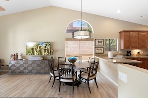 A modern kitchen with a dining area, featuring a round table with chairs, a built-in oven, and a large window. - Desert Retreat with Pool Near Golf & Hiking (Scottsdale)