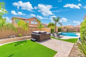 A backyard with a hot tub, a swimming pool, artificial grass, and a brick patio. - Desert Retreat with Pool Near Golf & Hiking (Scottsdale)
