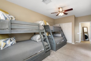 A room with bunk beds, a ceiling fan, and a door leading to another room. - Desert Retreat with Pool Near Golf & Hiking (Scottsdale)