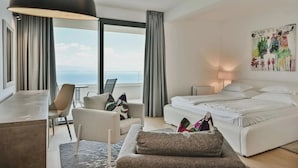 A hotel room with a bed, a desk, a chair, a sofa, a window with curtains, and a painting on the wall. - Villa Maremont Nearby Opatija - Crovillas (Opatija)