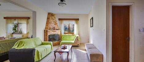 Un salon avec une cheminée, deux canapés, une table basse et une porte.