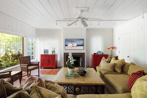 A living room with a fireplace, a television, and a ceiling fan. - The Original Beach House: A Timeless Gulf-Front Retreat on Siesta Key Beach (Sarasota)