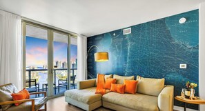 Ein modernes Wohnzimmer mit großem Fenster, einer Couch mit orangefarbenen Kissen und einer Wandkarte.