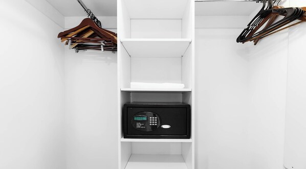 A white closet with shelves, a hanging rack, and a black safe. - New! Marina Panorama 2BR - Bay View Fitness Center (Hallandale Beach)