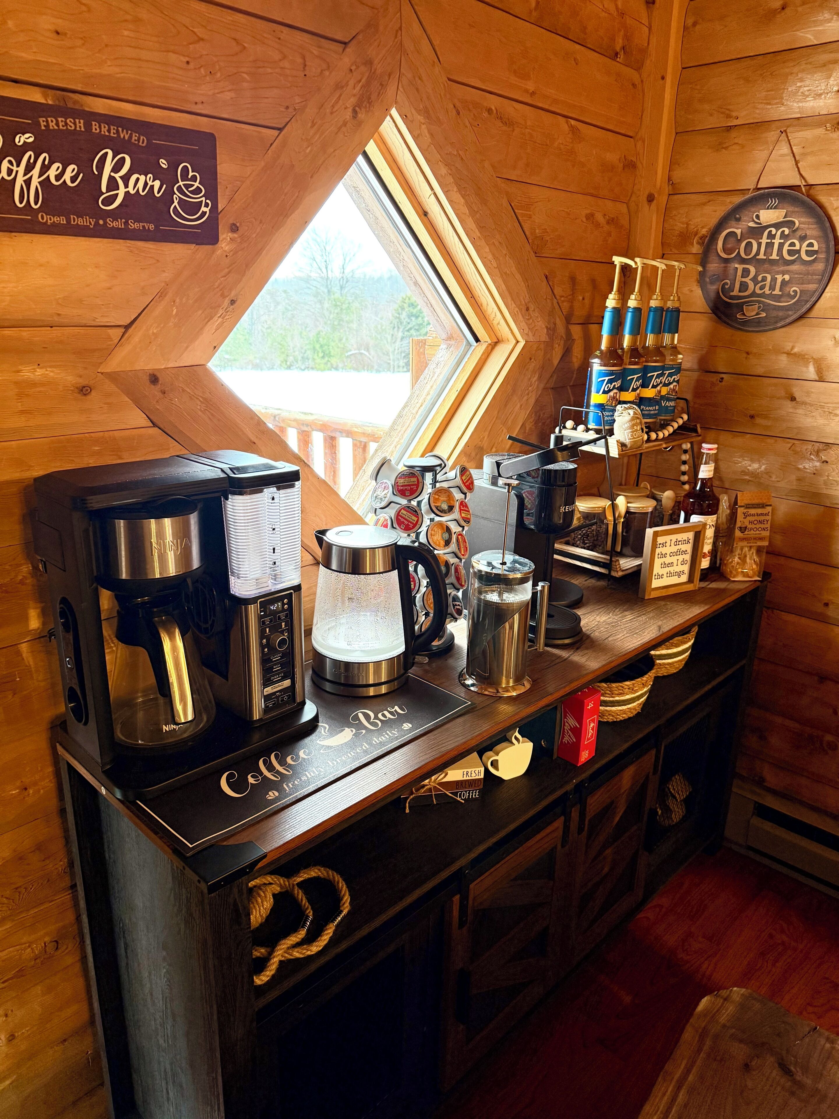 A coffee bar with a wooden interior, a coffee machine, a kettle, and various coffee-related items on display.
