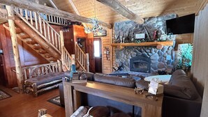 A wooden interior with a stone fireplace, a staircase, and a sofa. - Family friendly 3-bedroom cabin in peaceful Vanderbilt. Private. Large groups. (Vanderbilt)