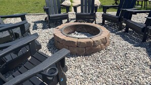 A wooden cabin with a stone chimney, a deck with chairs, and a fire pit surrounded by Adirondack chairs. - Family friendly 3-bedroom cabin in peaceful Vanderbilt. Private. Large groups. (Vanderbilt)