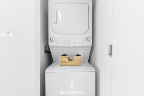 A white Beachwalk branded washing machine with a front-loading door, control panel, and a basket for laundry. - Airy 1BR - Bay View - Resort Amenities & Gym (Hallandale Beach)