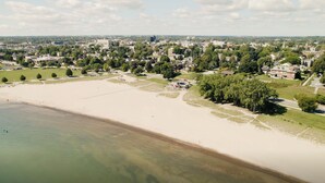 Une vue aérienne d’une plage, avec un ciel dégagé, entourée de zones résidentielles et de verdure.