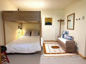 Ein Schlafzimmer mit einem Etagenbett, einem Nachttisch, einem Stuhl, einem gewebten Korb, einem Spiegel und einem Teppich.