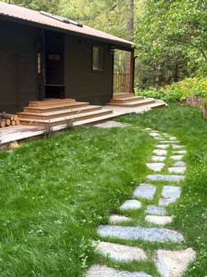 Eine Holzhütte mit einer Veranda und Steinstufen, die zu einer Tür führen.
