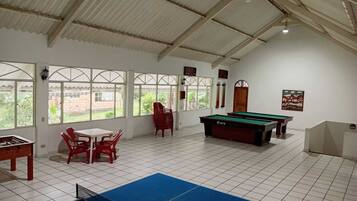 A room with a pool table, a ping pong table, and a billiards table.