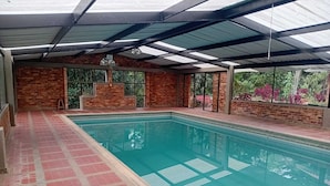 Ein Innenpool mit gefliestem Boden, Ziegelwänden und einer Glasdecke.