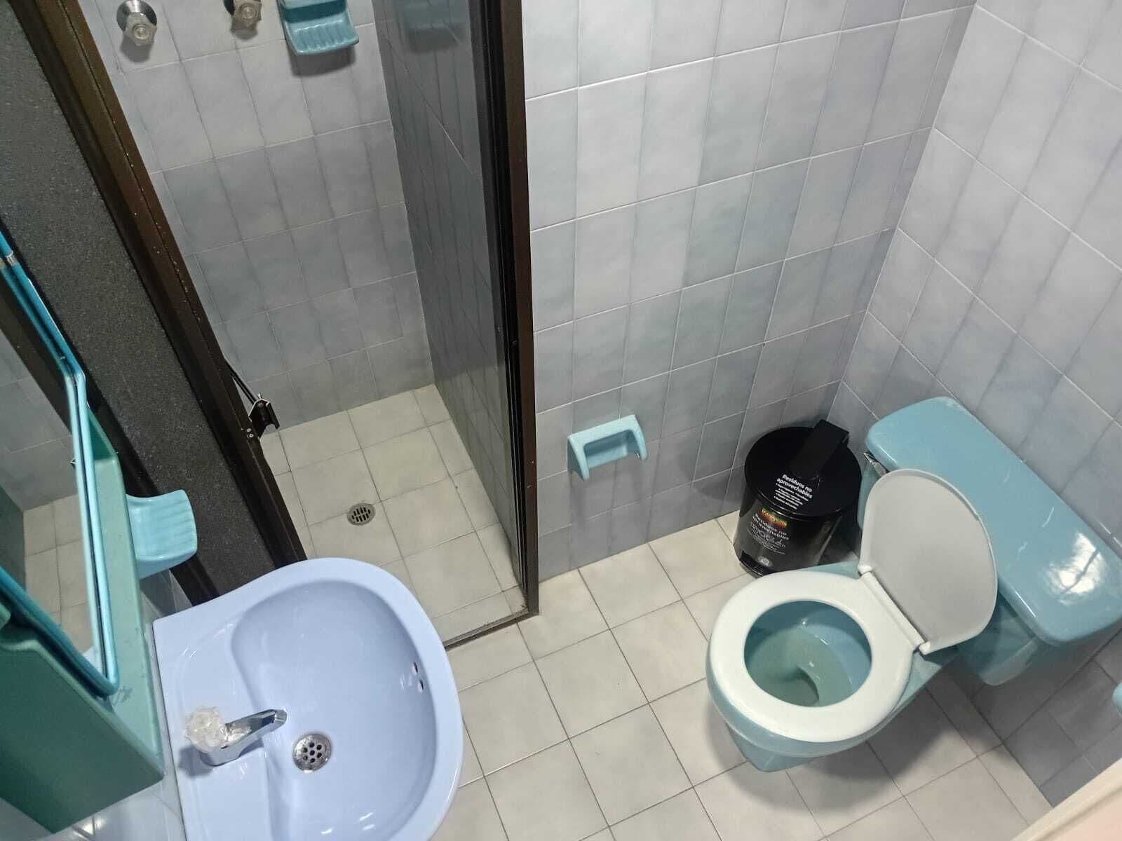 A bathroom with a sink, toilet, and a trash bin.