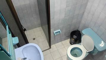 A bathroom with a sink, toilet, and a trash bin.