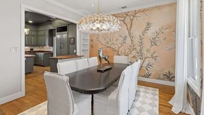 A dining area with a large table, white chairs, and a chandelier. - Painted Lady - Pool, Hot Tub & Walk to Main (Fredericksburg)