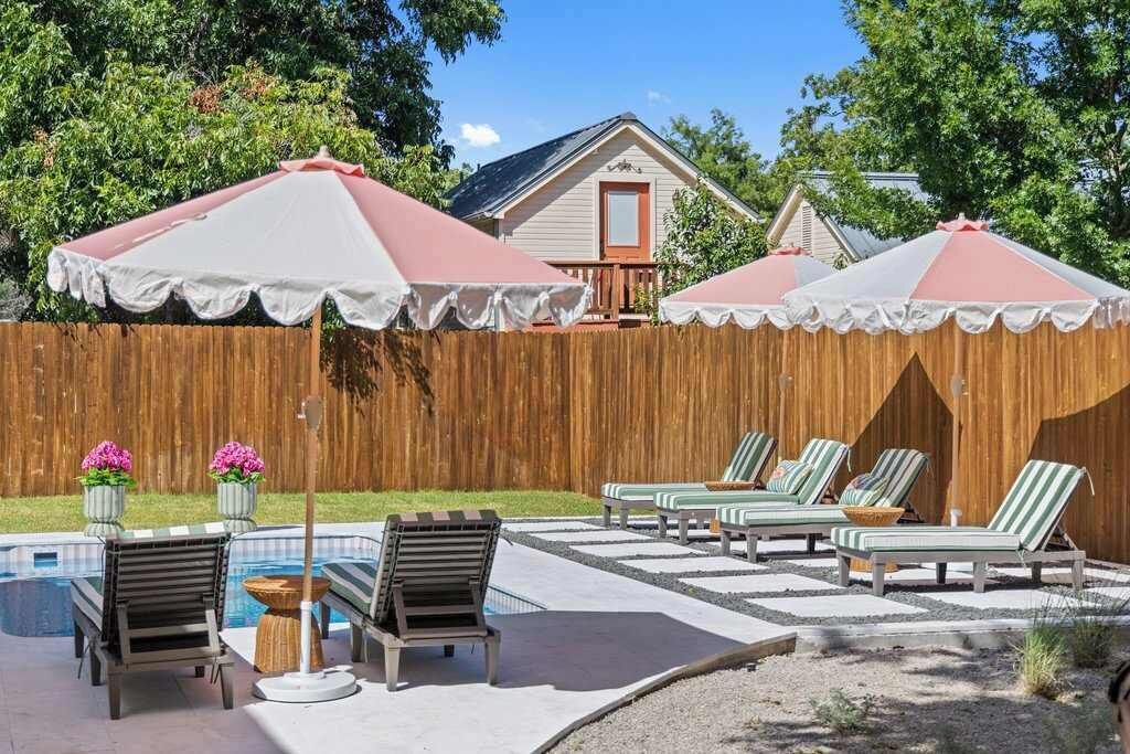 Ein Garten mit Pool, Liegestühlen und Sonnenschirmen.