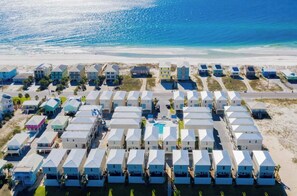 Ein Strandhotel mit mehrstöckigen Gebäuden, einem Schwimmbad und einer Straße zum Strand.
