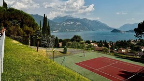 Ein Tennisplatz mit Blick auf einen See und Berge im Hintergrund.