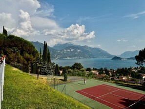 A tennis court with a view of a lake and mountains in the background. - Vista Lago 99 is a newly renovated apartment (Plesio)