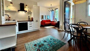 Eine moderne Küche mit weißen Schränken, einem roten Sofa und einem Essbereich mit Tisch und Stühlen.