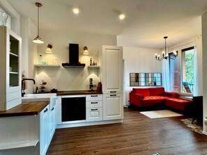 Une cuisine moderne avec des meubles blancs, une hotte noire et des luminaires suspendus.