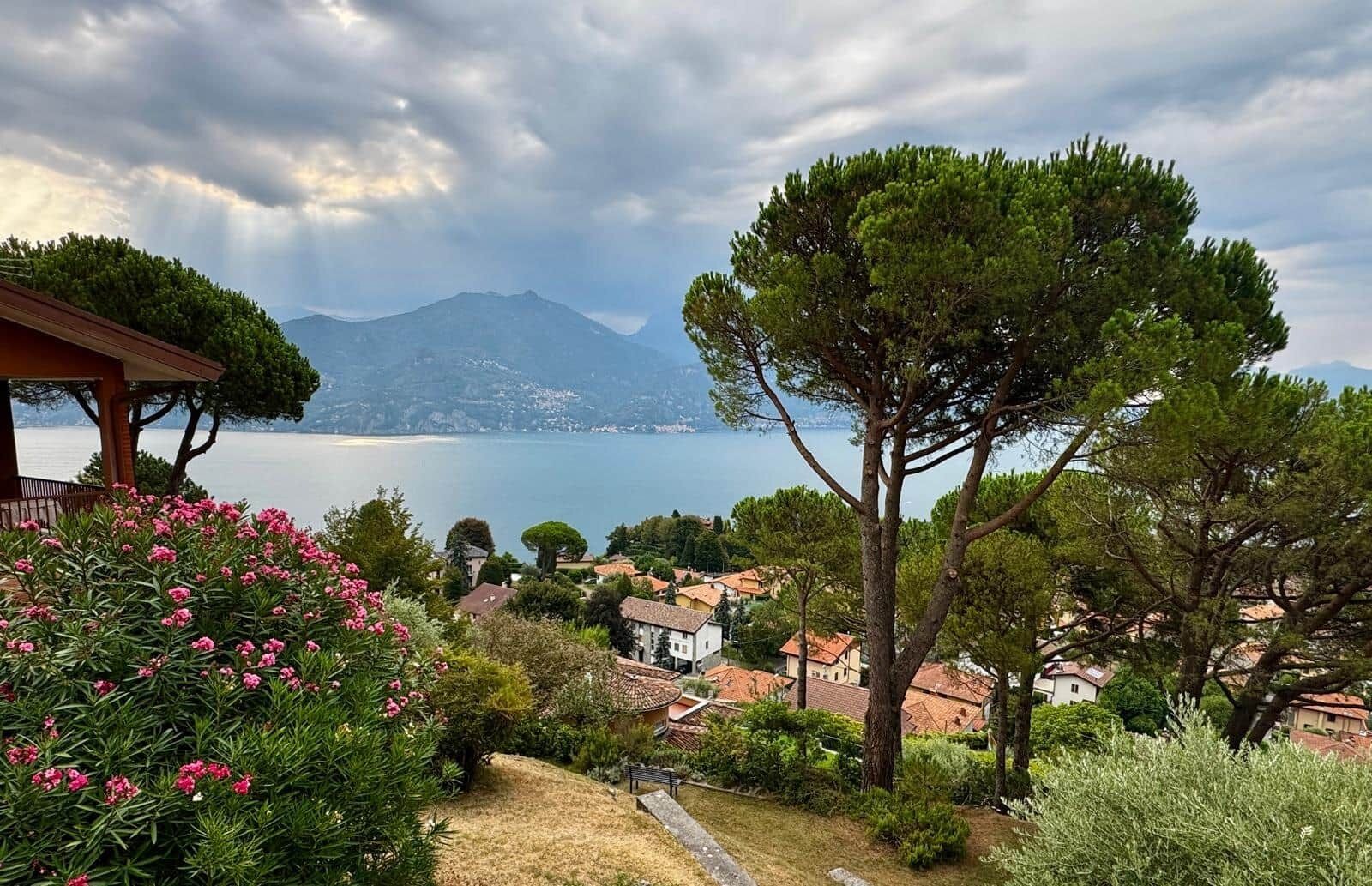 A coastal landscape with a clear view of the sea, a mountain in the distance, and a residential area with houses and trees.