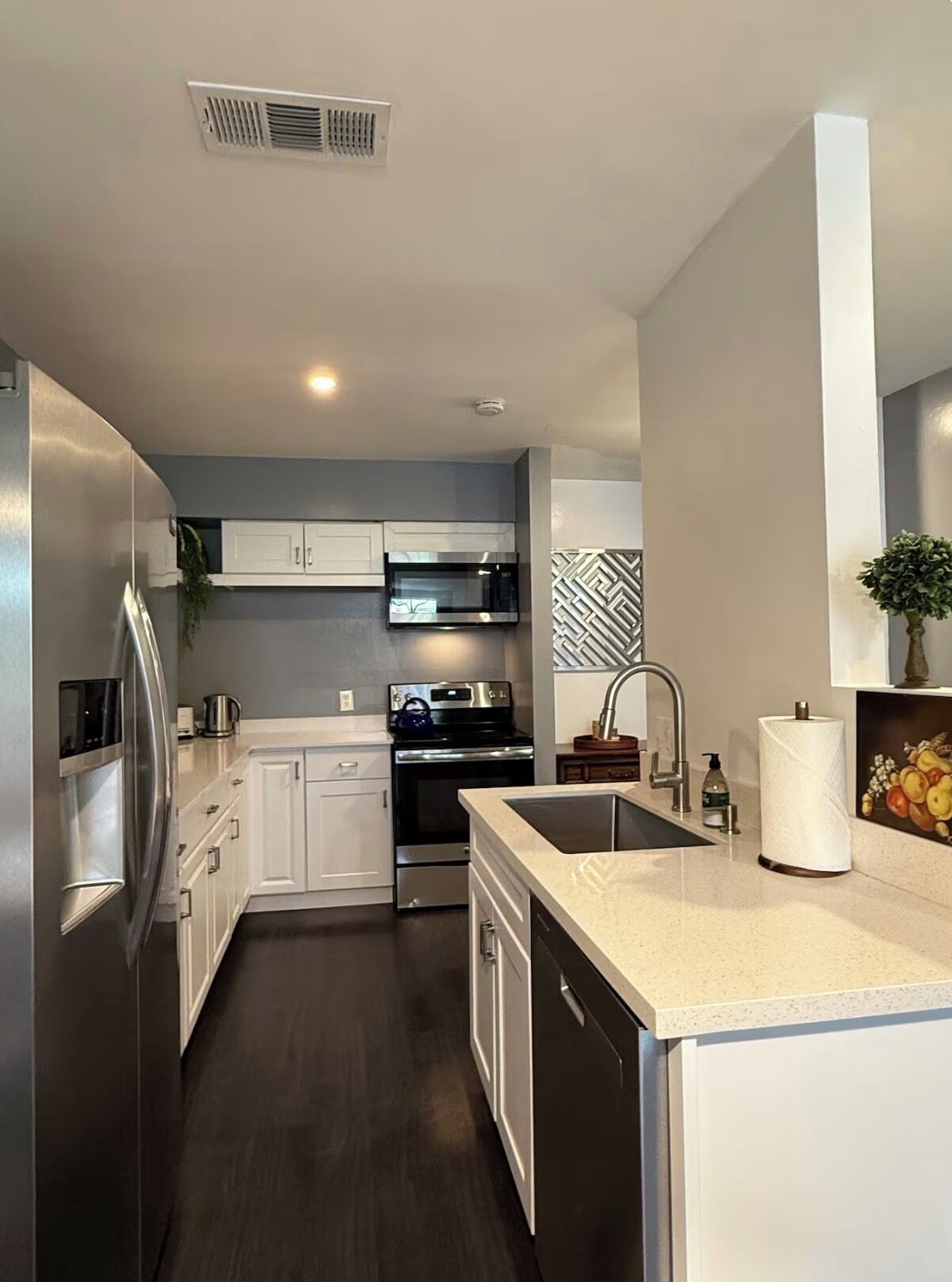 A modern kitchen with white cabinets, stainless steel appliances, a dishwasher, and a sink.