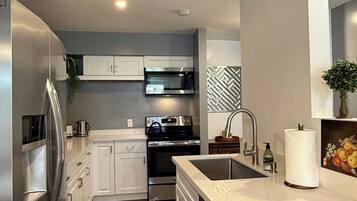 A modern kitchen with white cabinets, stainless steel appliances, a dishwasher, and a sink.