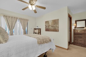 A bedroom with a bed, a ceiling fan, a painting, a dresser, and a window with curtains. - Sasquatch Beech 3BR Beech Mountain Home- Near Skiing- Fire pit- Sleeps 8 (Beech Mountain)