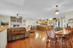 A spacious living room with a fireplace, a dining area with wooden chairs, and a kitchen with wooden cabinets. - Sasquatch Beech 3BR Beech Mountain Home- Near Skiing- Fire pit- Sleeps 8 (Beech Mountain)