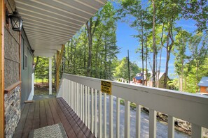 A wooden deck with a railing, a stone wall, and a caution sign warning of slippery when wet. - Sasquatch Beech 3BR Beech Mountain Home- Near Skiing- Fire pit- Sleeps 8 (Beech Mountain)