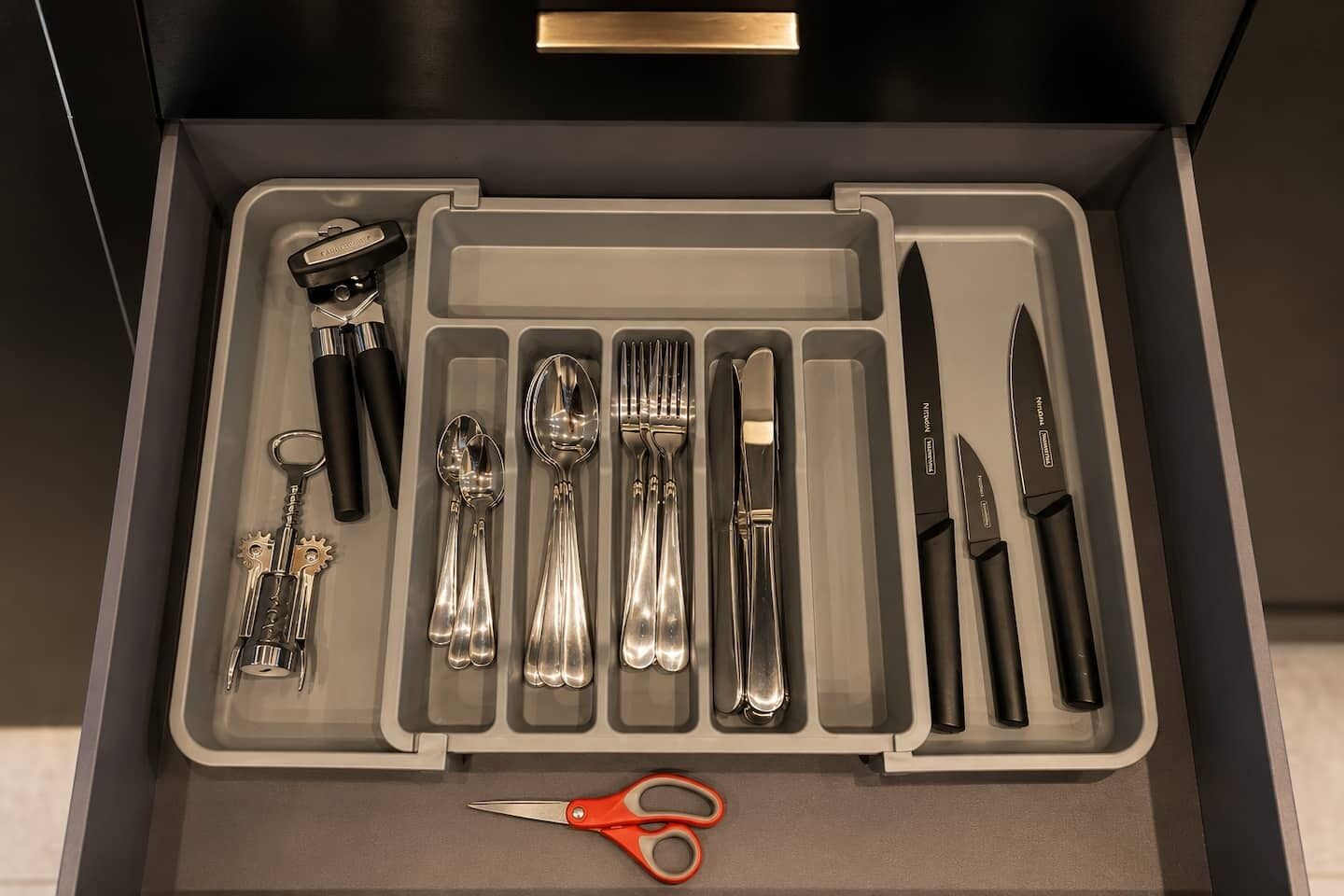 A drawer with a knife set, spoon set, fork set, and a pair of scissors.