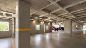 Eine mehrgeschossige Parkgarage mit Betonpfeilern, gekennzeichneten Stellplätzen und freiem Blick zum Himmel durch die Fenster.