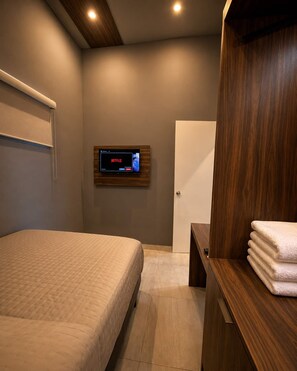 Une chambre à coucher moderne avec un lit, une armoire en bois, un téléviseur fixé au mur et une porte.