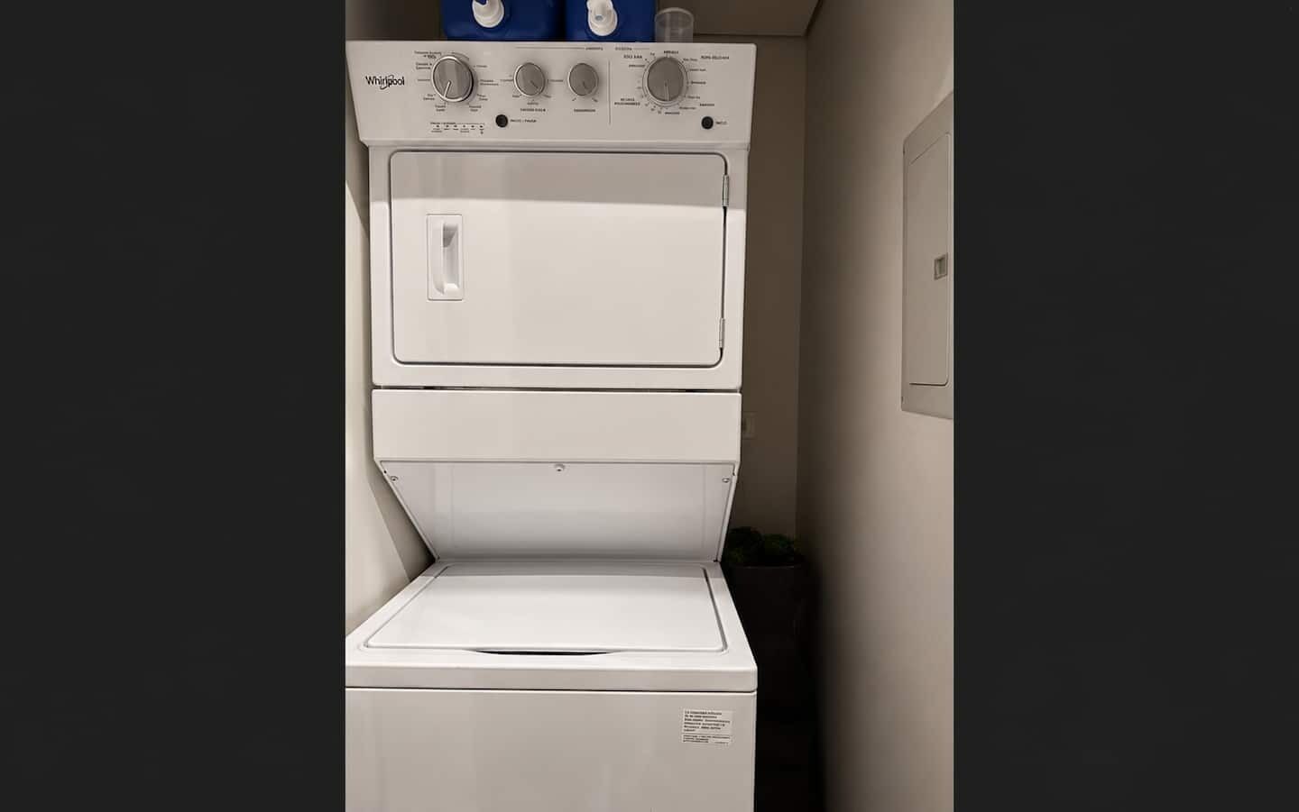 A Whirlpool stacked washer and dryer unit with control knobs and a door.