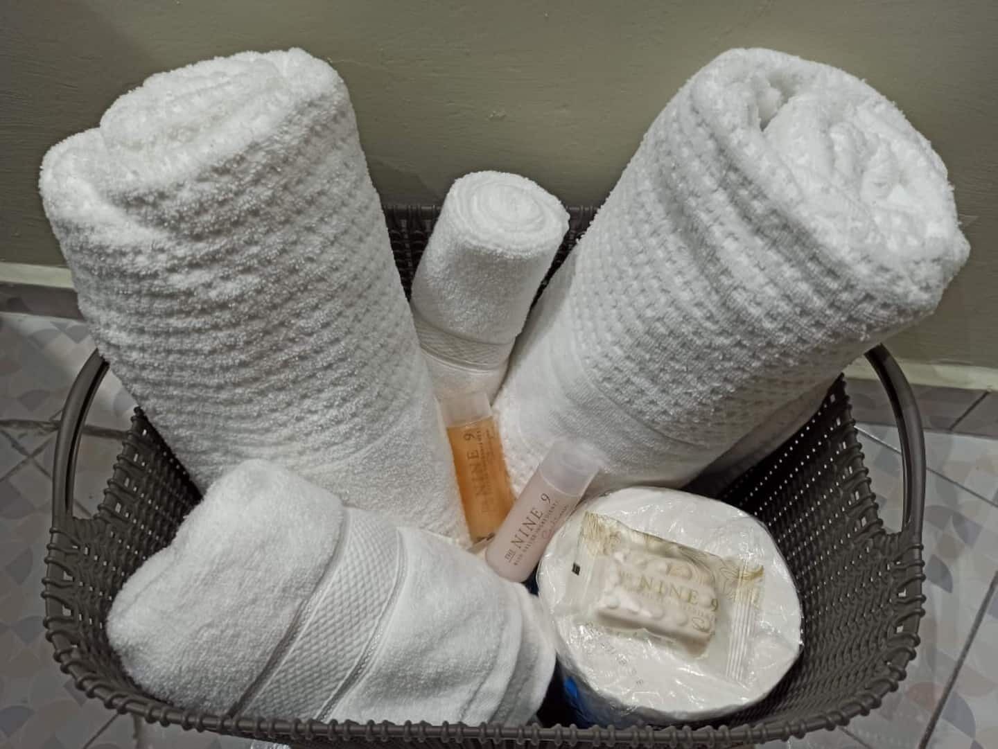 Un panier contenant des serviettes enroulées et une bouteille de lotion.