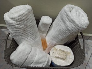 A basket containing rolled towels and a bottle of lotion.