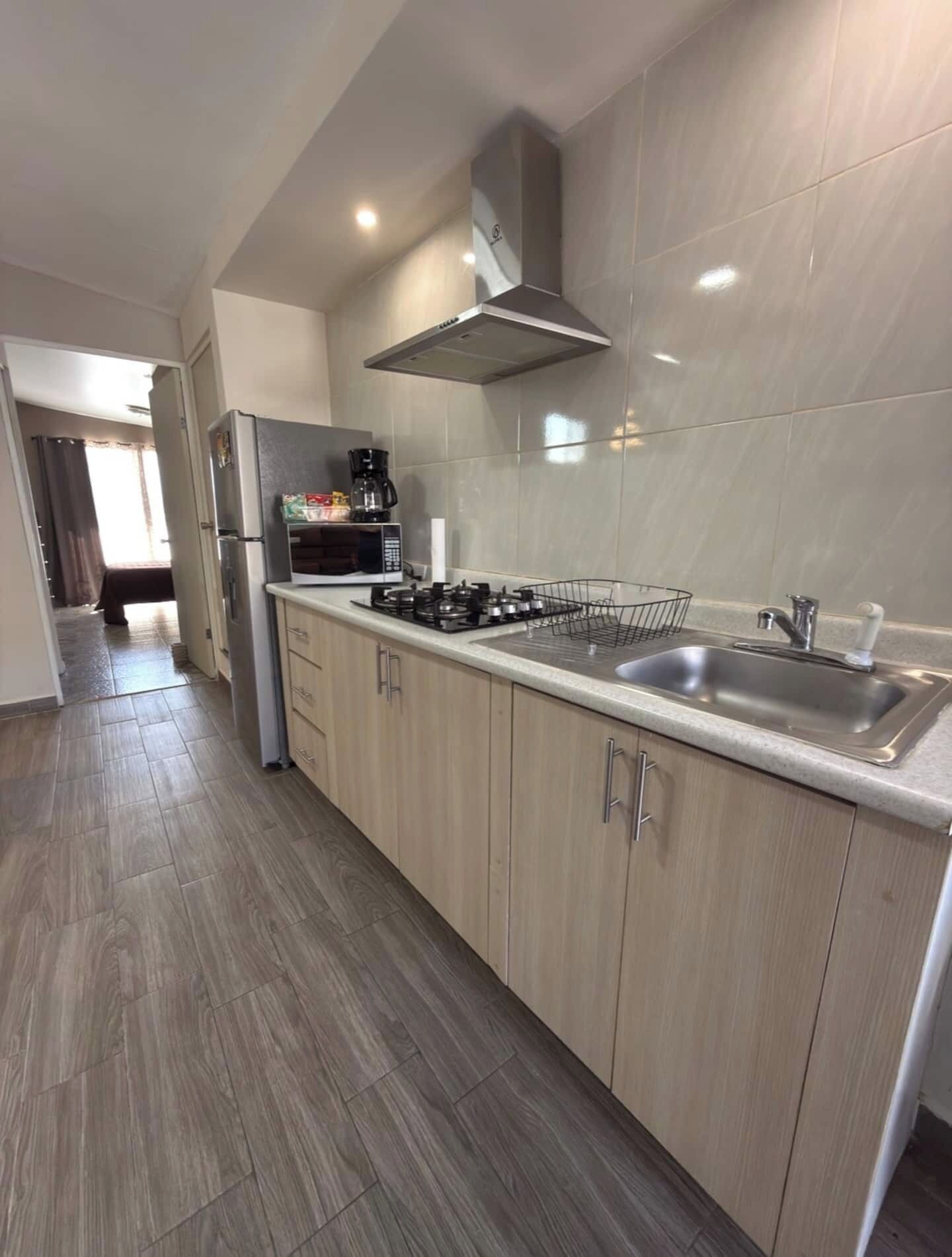A modern kitchen with a stainless steel sink, a gas stove, and a microwave.
